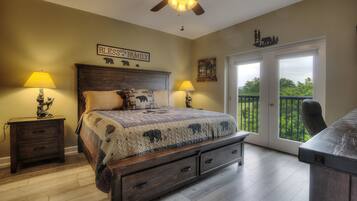 A bedroom with a bed, two nightstands, a ceiling fan, a large window, and a balcony.
