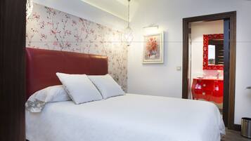 Una cama bien hecha con ropa blanca y un cabecero rojo.