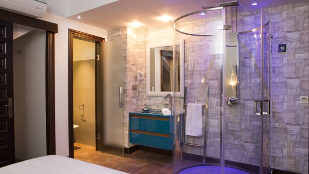 Un baño moderno con ducha envuelta en vidrio, tocador con espejo y retrete.