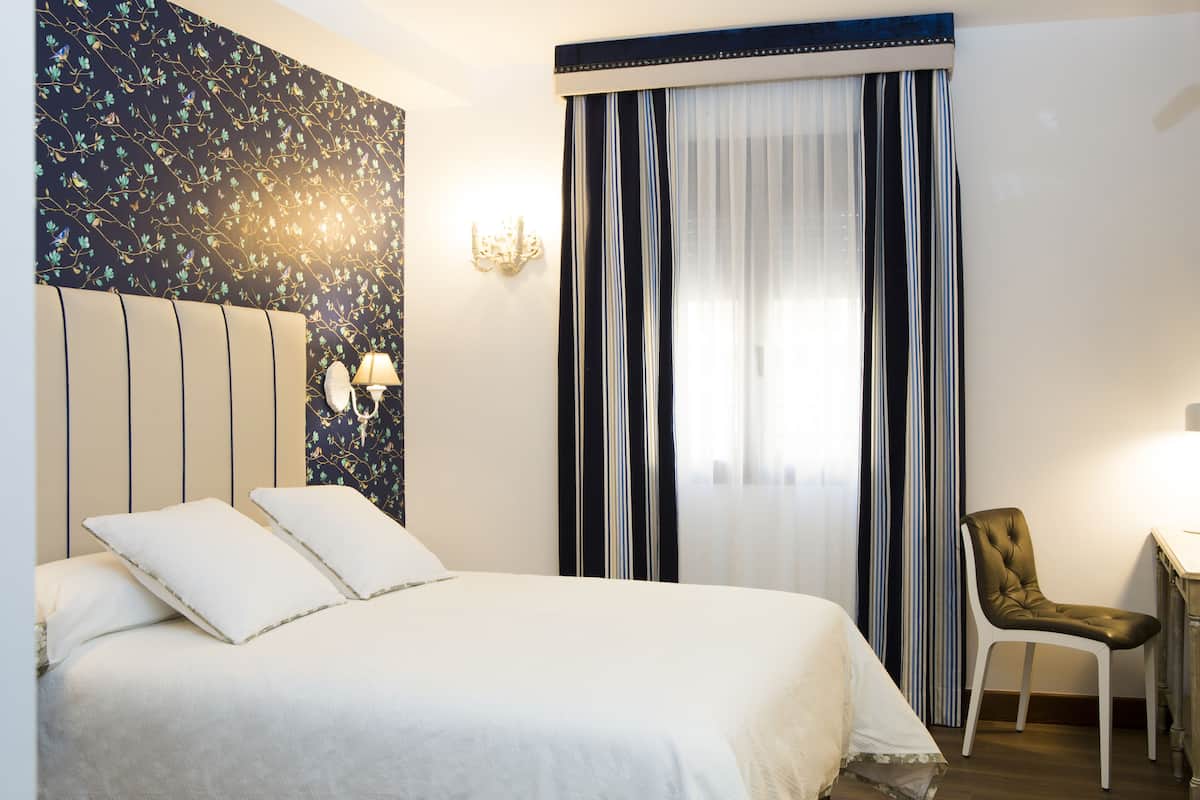 A hotel room with a large bed, a desk, and a chair.