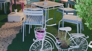 Un espacio al aire libre con mesas y sillas, rodeado de sombrillas blancas y plantas en macetas.