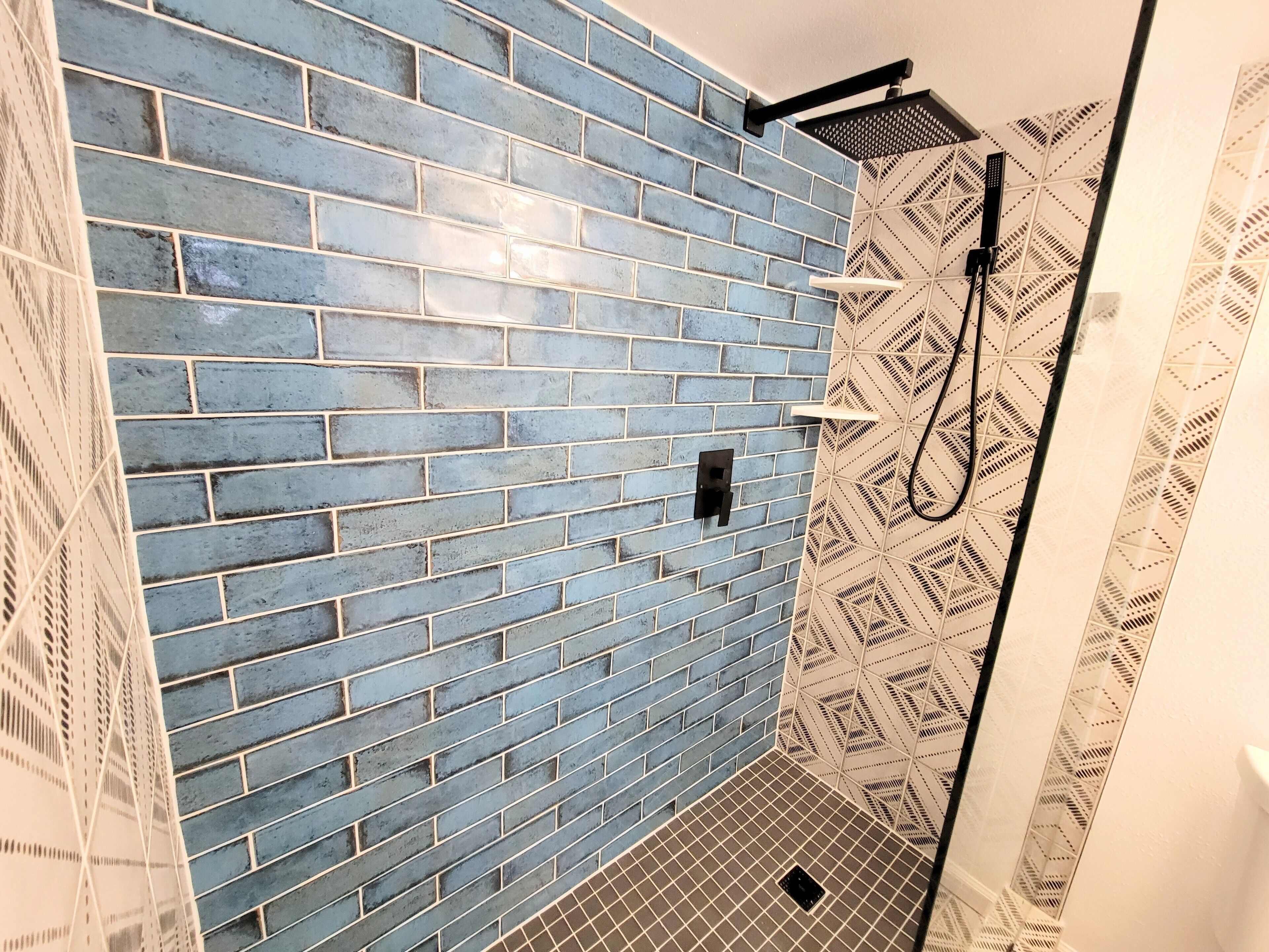 A bathroom with blue brick walls and patterned tiles.