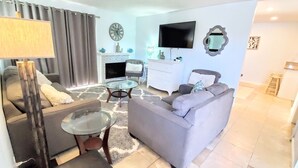 A modern living room with a fireplace, a flat-screen TV, and a sofa.