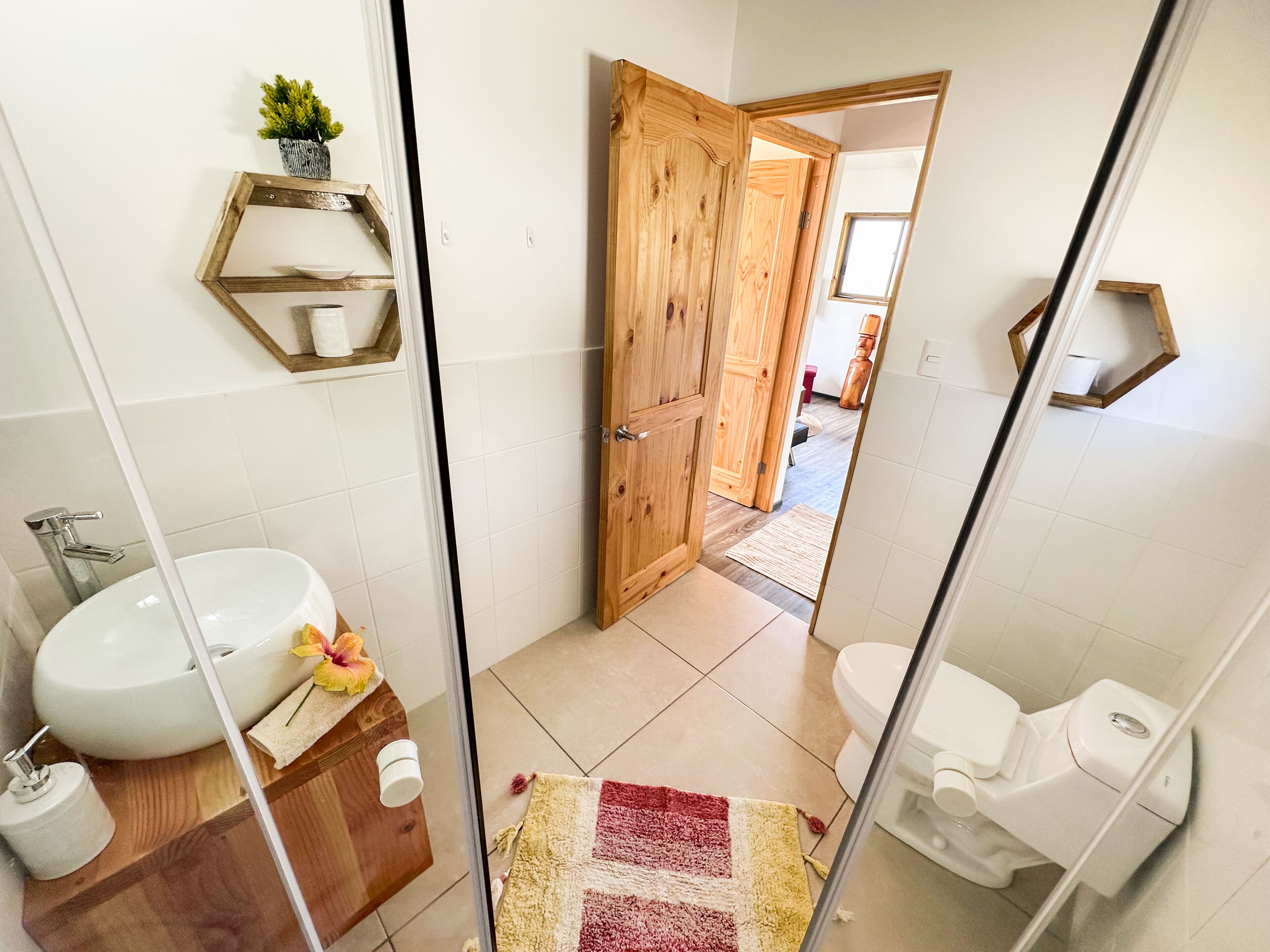 A bathroom with a wooden door, a white sink, and a toilet.