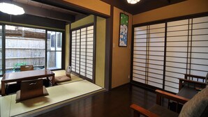 A traditional Japanese room with tatami flooring, shoji screens, and a low table with cushions. - Maeniiya Machiya Inn (Kyoto)