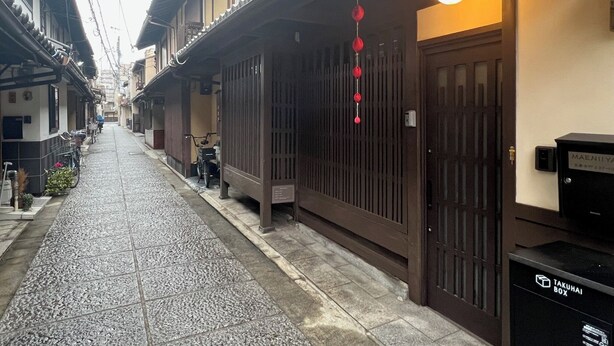 A narrow street with traditional buildings, a bicycle, and a mailbox. - Maeniiya Machiya Inn (Kyoto)
