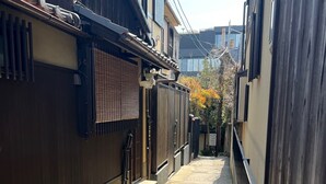 A narrow alleyway between traditional wooden buildings with tiled roofs and a stone pathway. - Kiyomizu Machiya Inn (Kyoto)