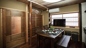 A traditional Japanese-style room with tatami flooring, a low table with a TV, and sliding doors. - Kiyomizu Machiya Inn (Kyoto)