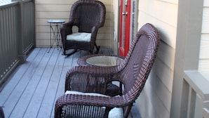 Une véranda couverte avec deux fauteuils à bascule en osier et une petite table ronde.