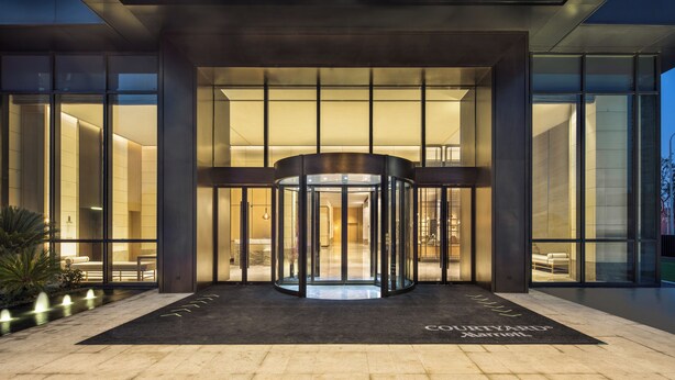 Een moderne hotelentree met een draaideur, grote glasramen en een goed verlicht interieur.