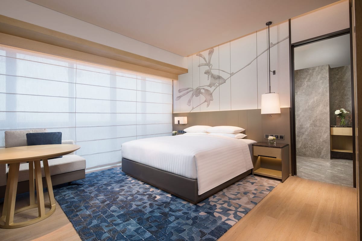 Ein modernes Hotelzimmer mit einem großen Bett, einem kleinen Tisch und einer Sitzecke.