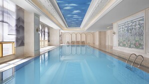 Une grande piscine intérieure avec une fresque représentant des nuages au plafond, un sol carrelé et un mur décoratif orné de motifs floraux.