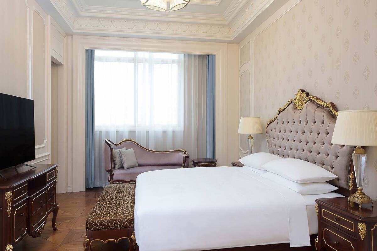 Une chambre d’hôtel avec un grand lit, une télévision, un canapé et une table de chevet avec des lampes.