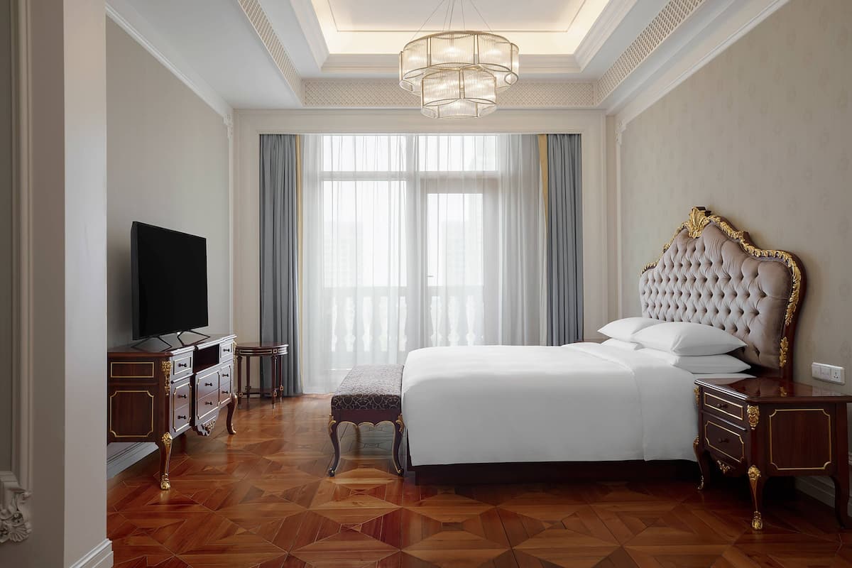 Une chambre spacieuse avec un grand lit, une télévision et un plancher en bois.