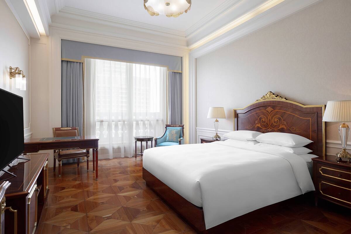 Une chambre d’hôtel avec un grand lit, un bureau, une chaise et un téléviseur.