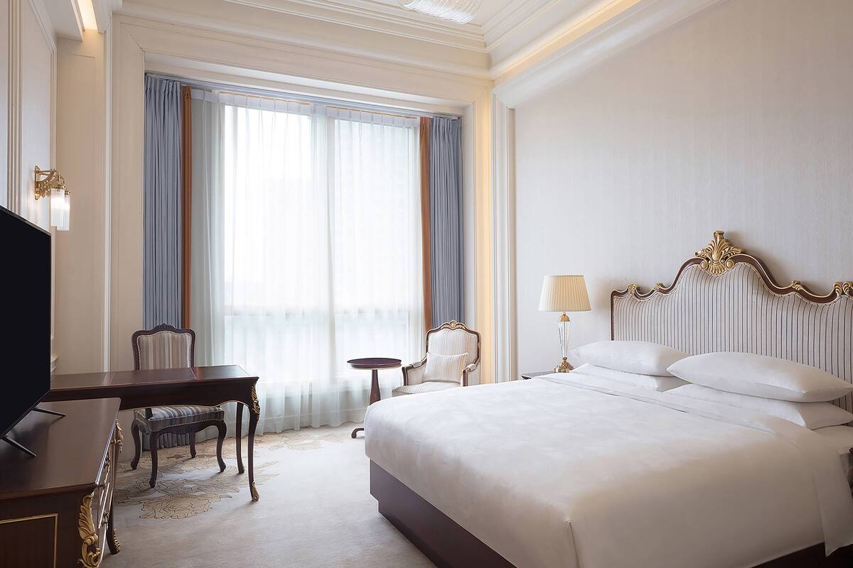 Une chambre d’hôtel avec un grand lit, un bureau, une chaise et un téléviseur.