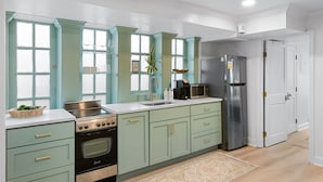 A kitchen with teal cabinets, a stainless steel stove, and a refrigerator. - Charming Historic 1BR w/ Private Porch + Free Parking (Charleston)