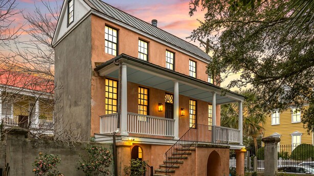 A two-story colonial-style house with a balcony, a front porch, and a staircase leading to the second floor. - Charming Historic 1BR w/ Private Porch + Free Parking (Charleston)