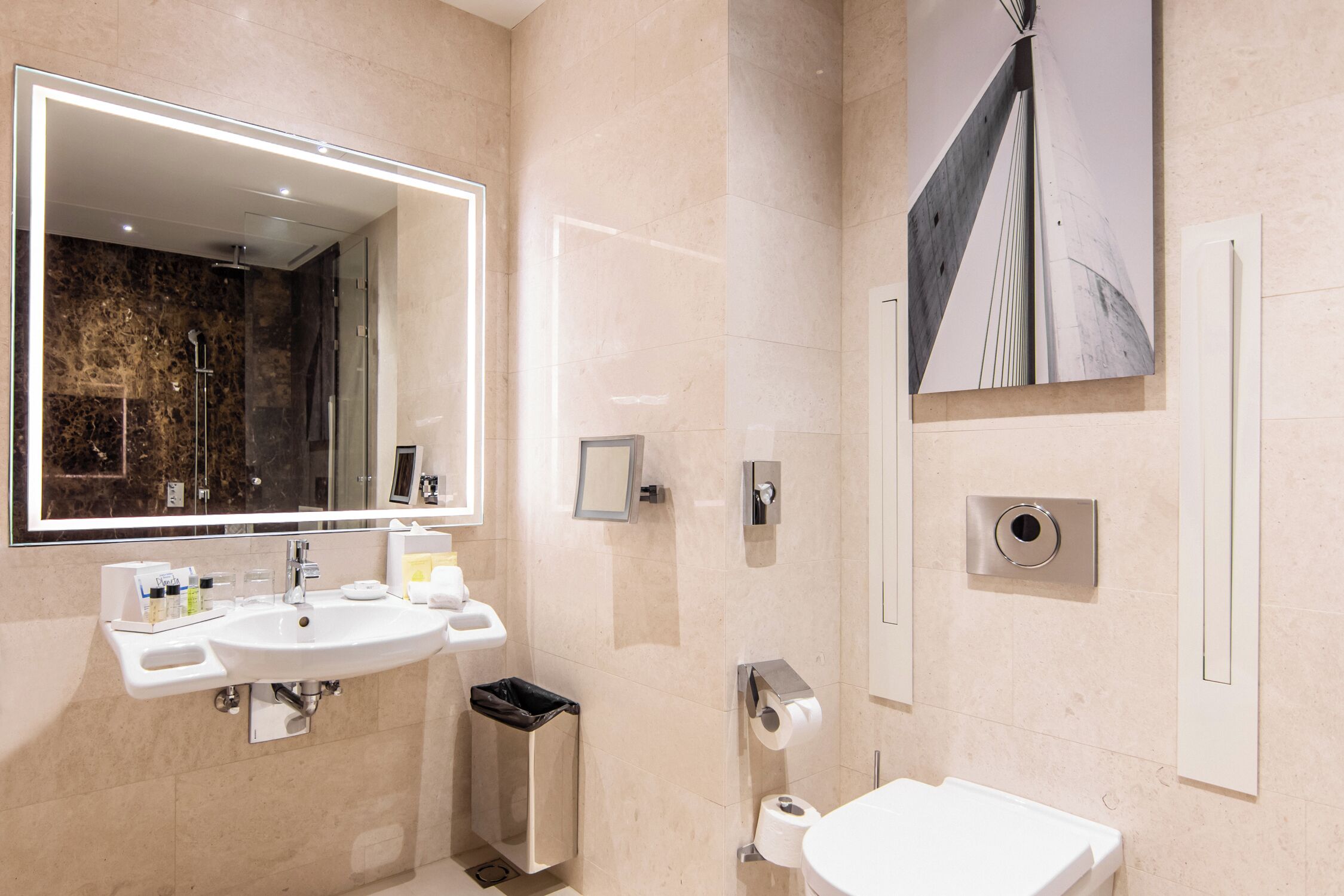 A modern bathroom with a large mirror, dual sinks, a toilet, and a shower.