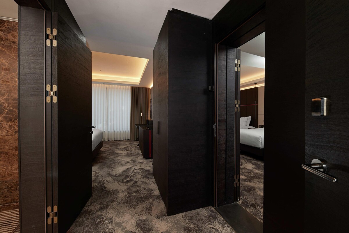 A hotel room with a bed, a desk, and a mirror.