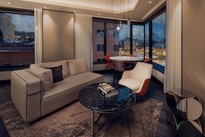 A modern living room with a sofa, a round coffee table, and a dining area with chairs and a table. - Hilton Belgrade (Belgrade)