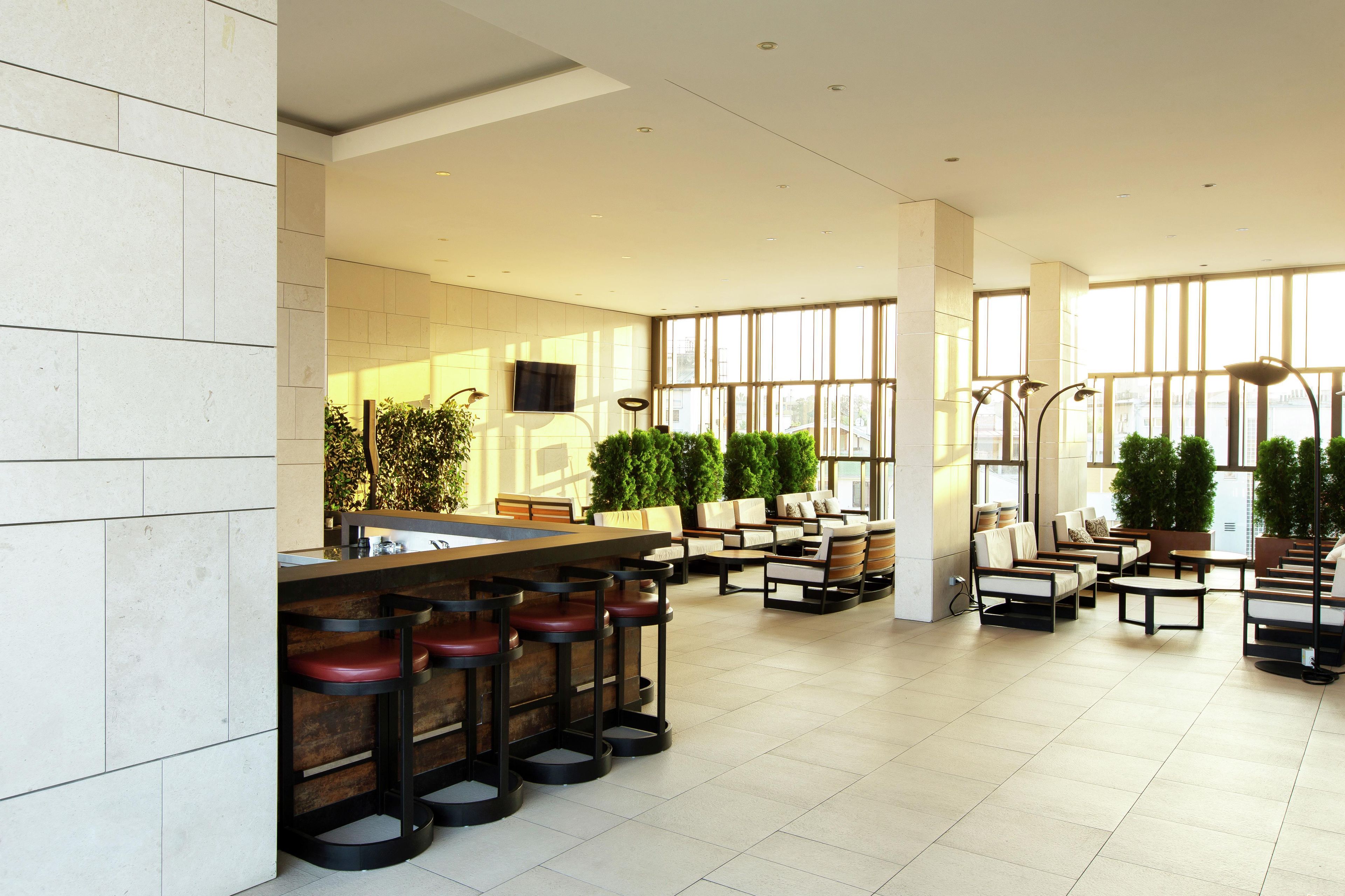 A spacious indoor area with a bar, seating, and large windows.
