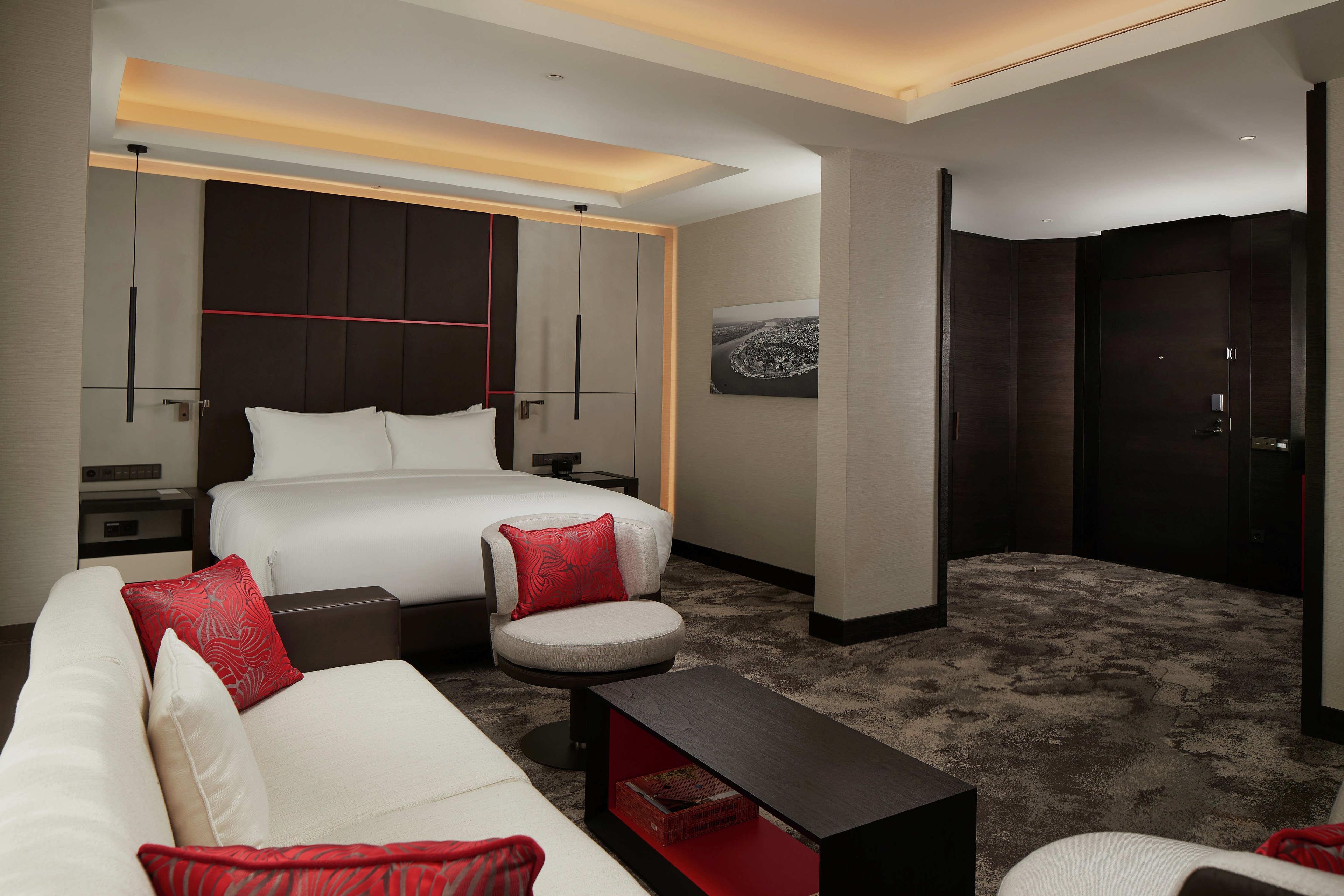 Una habitación de hotel moderna con una cama, un sofá, una mesa de centro y un escritorio.