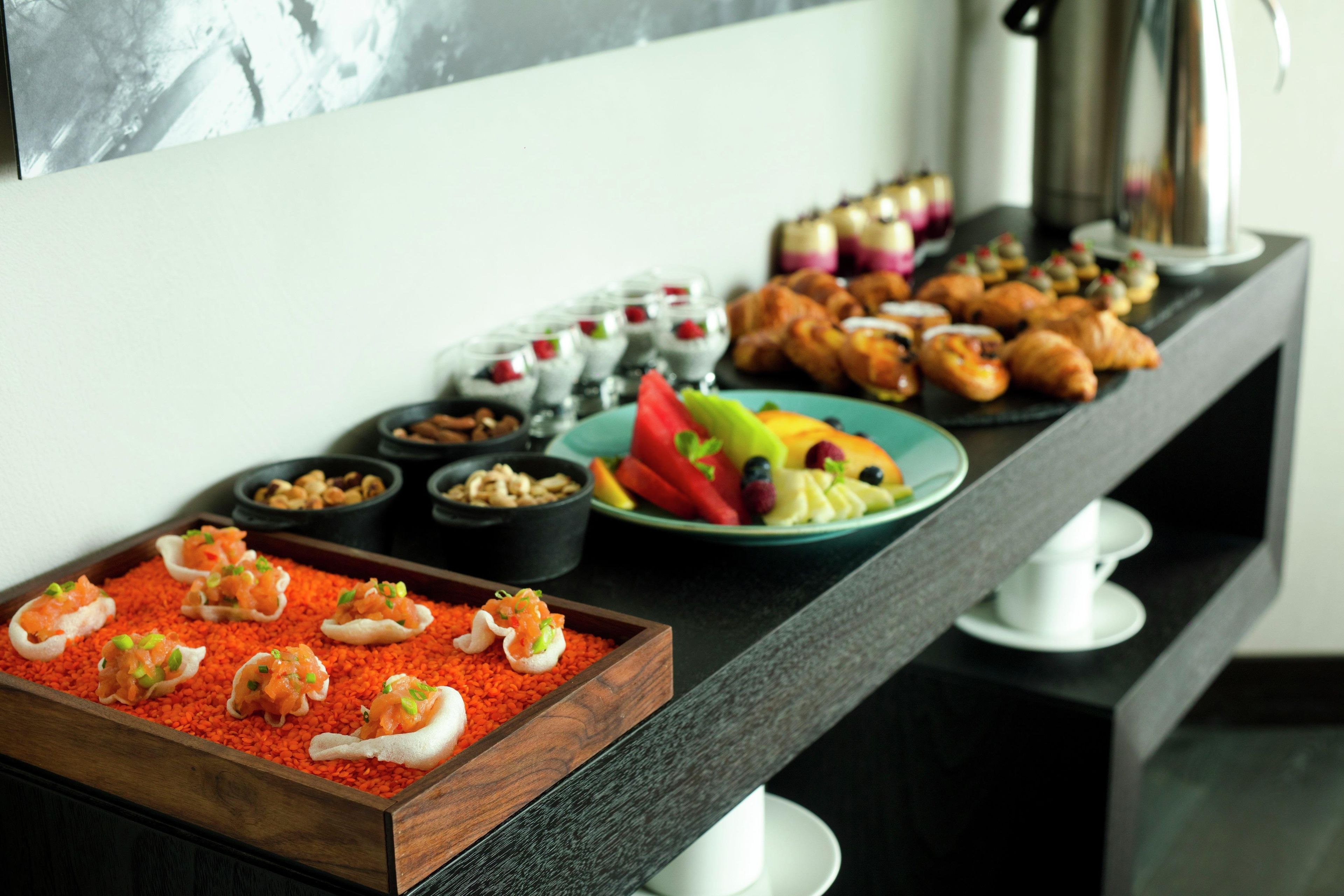Un buffet proposant une variété de plats, notamment des fruits, des pâtisseries et des amuse-gueules.
