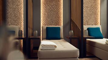 Un spa moderno con una camilla de masaje, dos mesitas auxiliares y paneles decorativos en la pared.