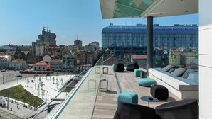 A rooftop terrace with seating, a glass balustrade, and a view of a cityscape including modern buildings. - Hilton Belgrade (Belgrade)