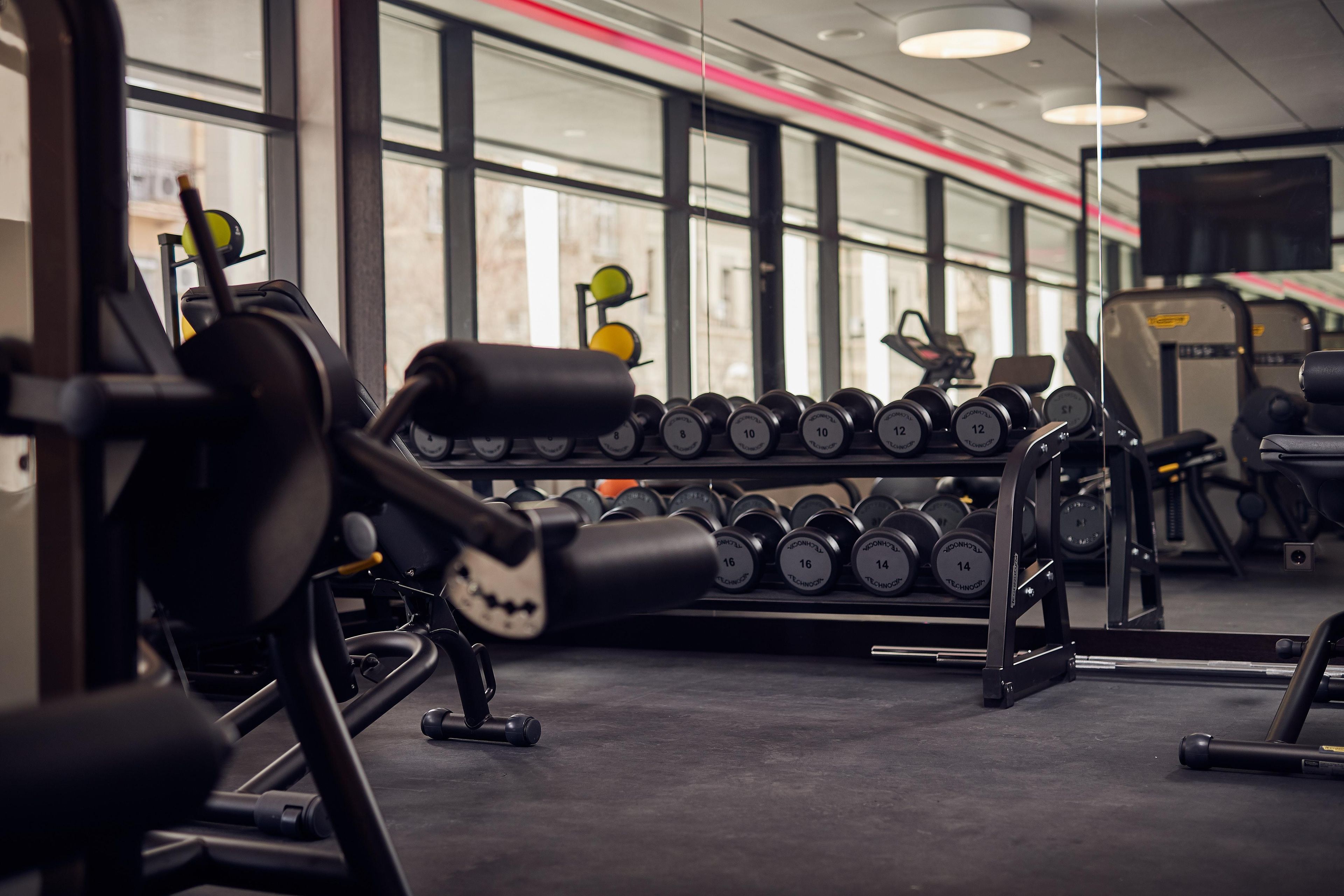 A gym with weightlifting equipment and dumbbells.