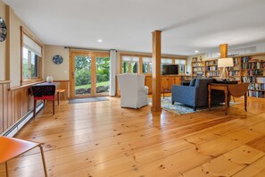 Un salon spacieux doté d’un parquet en bois, d’un fauteuil blanc, d’un canapé bleu et d’une bibliothèque remplie de livres.
