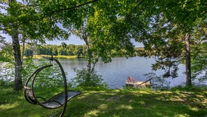 A hammock chair by a lake with a dock and a chair on the opposite side. - On Silver Lake Close To Woodstock (Barnard)