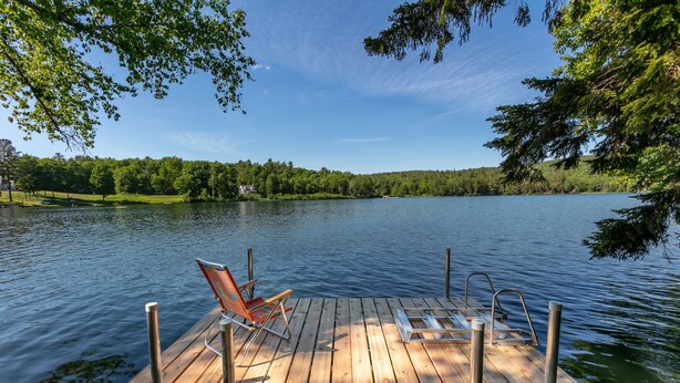 A wooden dock with a chair and metal railings extending over calm water. - On Silver Lake Close To Woodstock (Barnard)