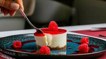 Una porción de pastel de queso con cobertura roja y frambuesas sobre un plato.