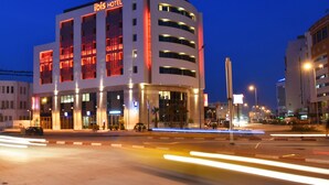 A modern hotel with a prominent "Ibis Hotel" sign, multiple floors, and a well-lit facade. - ibis Sfax (Sfax Ouest)