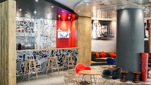 A modern interior with a bar area, seating, and a mural wall. - ibis Sfax (Sfax Ouest)