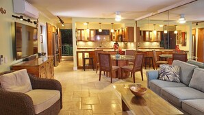 A modern kitchen with a dining area, a sofa, and a coffee table. - Poipu Shores 303A - Oceanfront Luxury w/ AC & Pool (Koloa)
