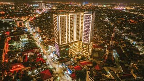 Een hoog hotel met meerdere verdiepingen, omgeven door een dichtbevolkt stedelijk gebied bij nacht.