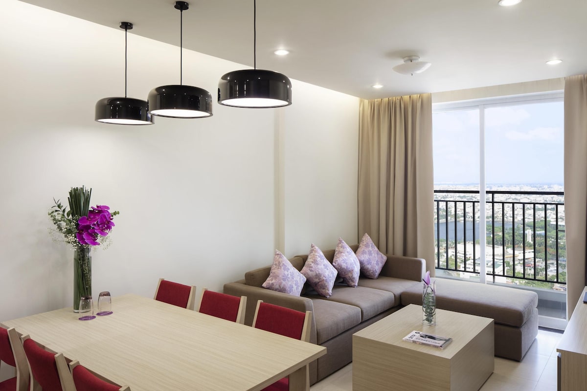 Een moderne woonkamer met een eetgedeelte, een zithoek en een balkon met uitzicht op de stad.