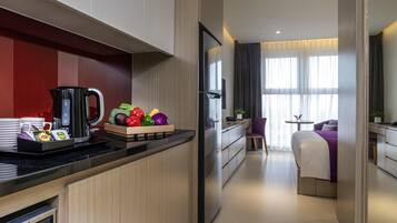 A modern hotel room with a kitchenette, a dining area, and a bed.