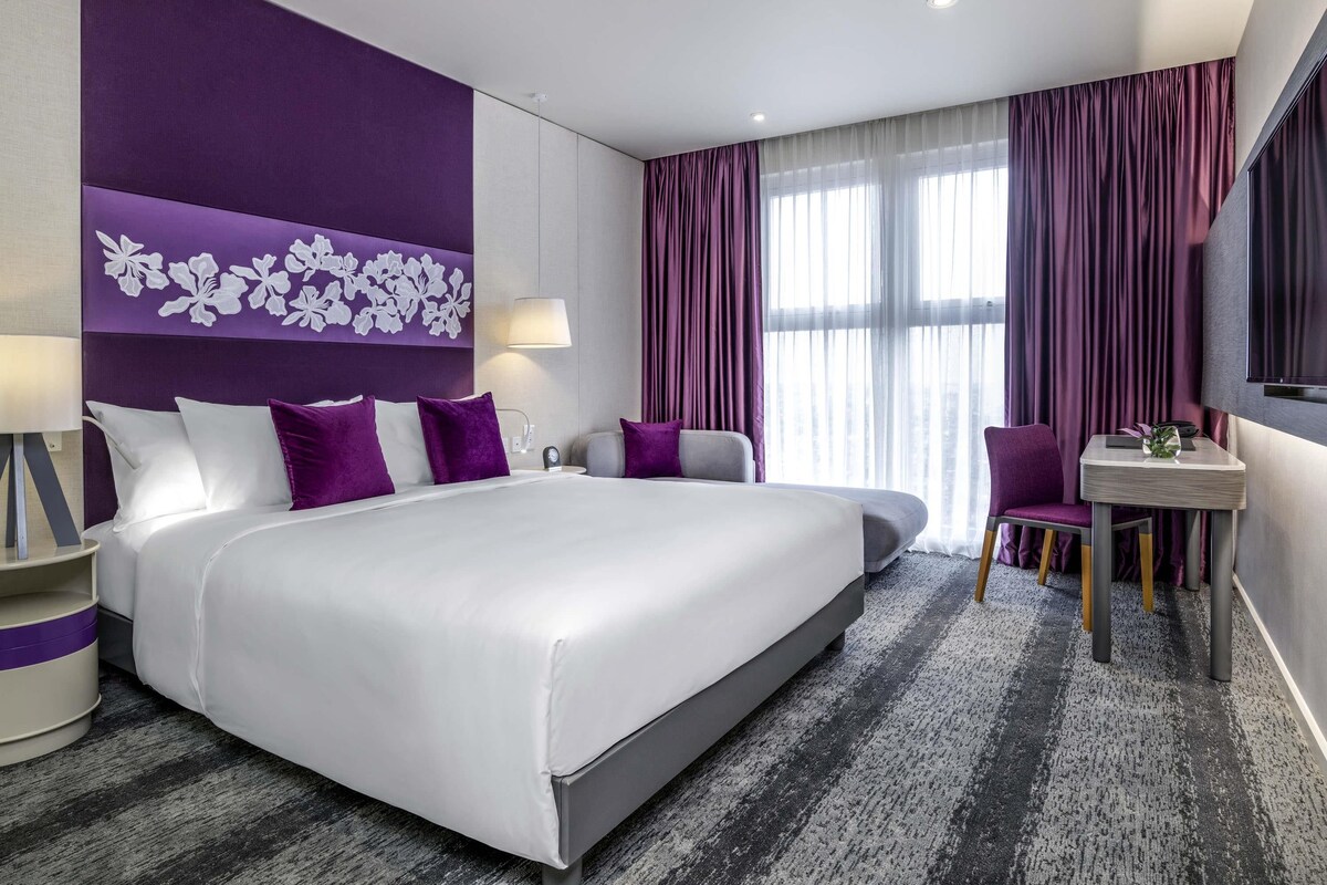 Een moderne hotelkamer met een groot bed, een bureau en een stoel.