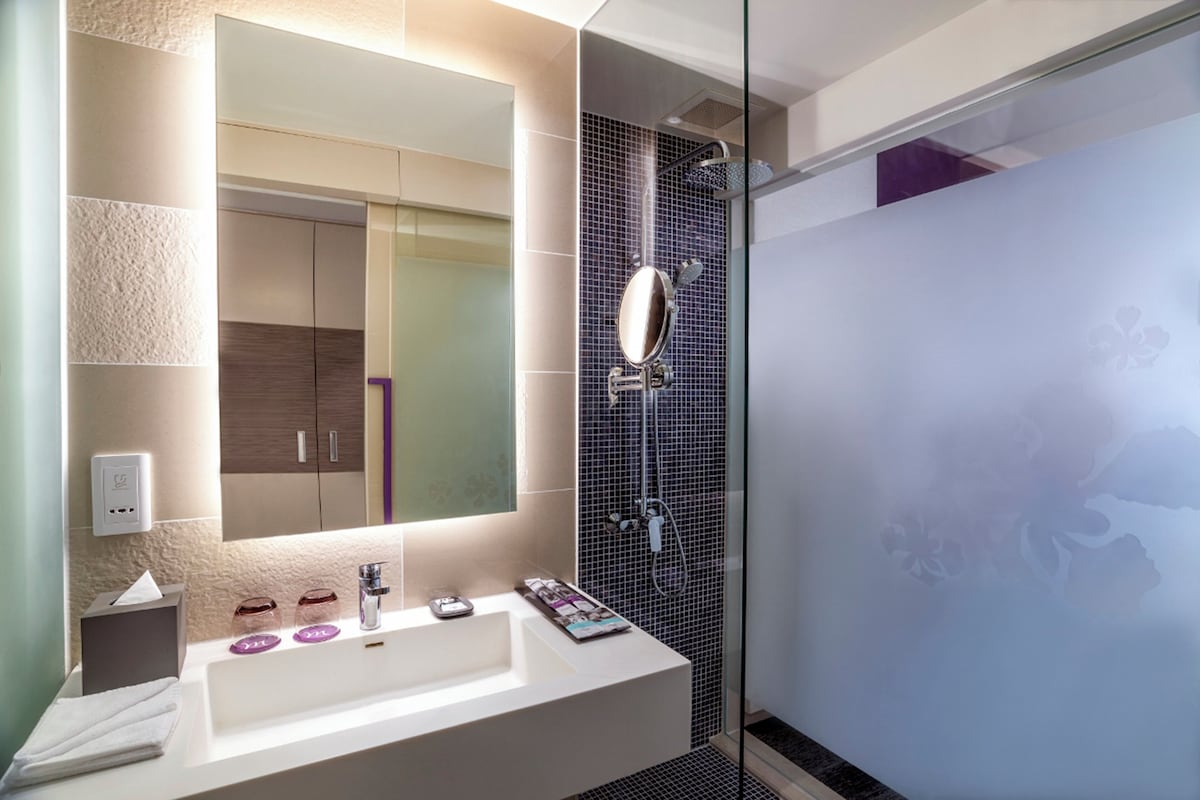 A modern bathroom with a large mirror, a sink, and a shower area.