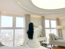 Una habitación con ventanas amplias, una cama, un escritorio y una silla.