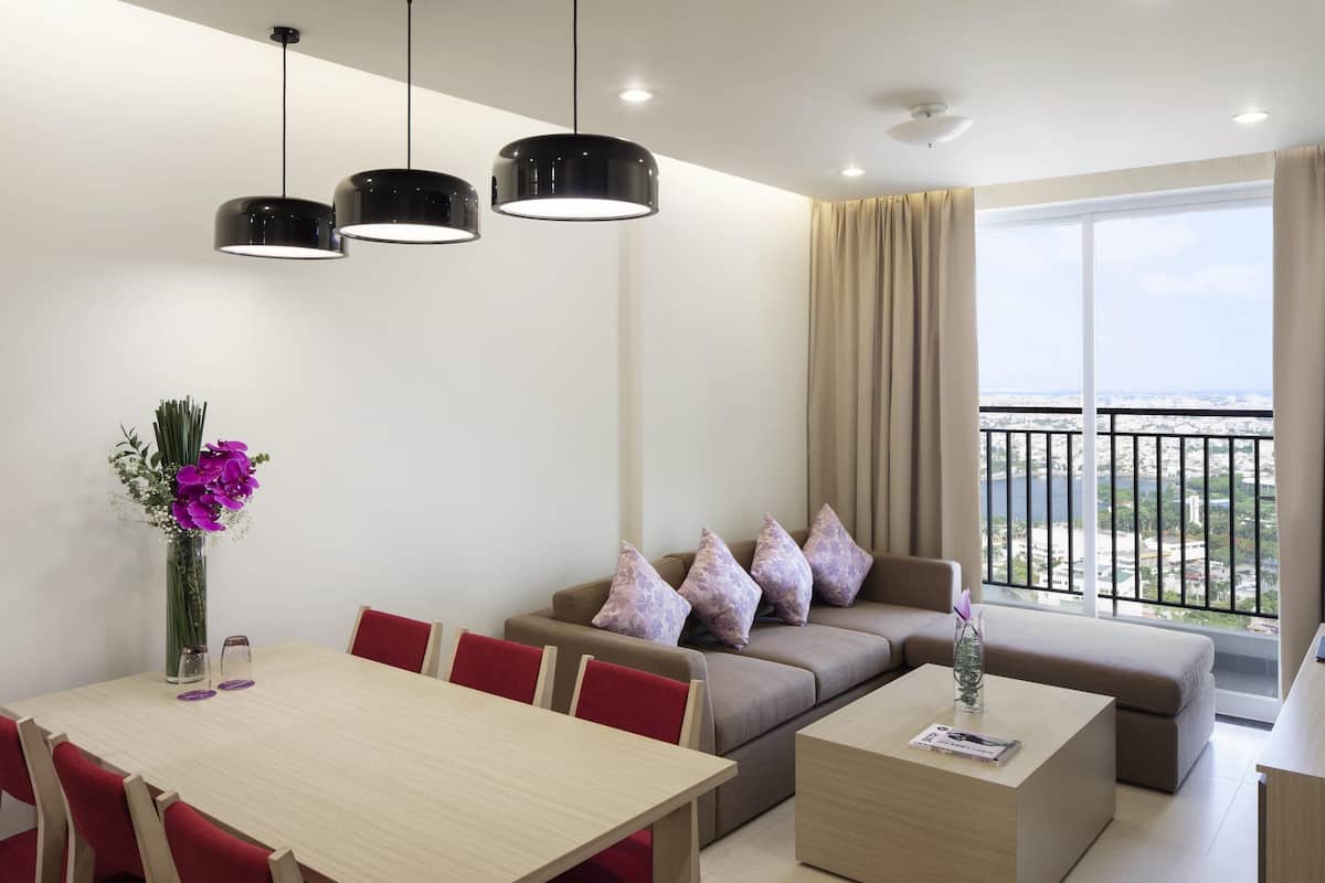 Een moderne woonkamer met een eetgedeelte, een zithoek en een balkon met uitzicht op de stad.