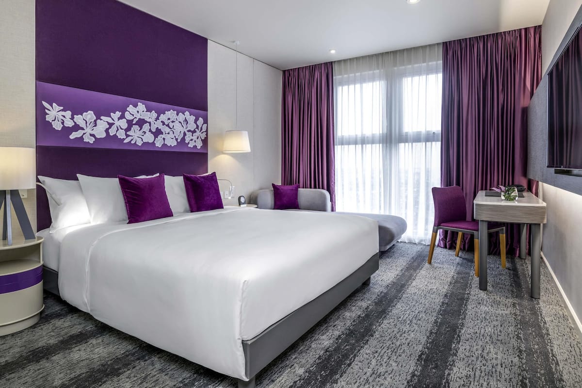 Een moderne hotelkamer met een groot bed, een bureau en een stoel.