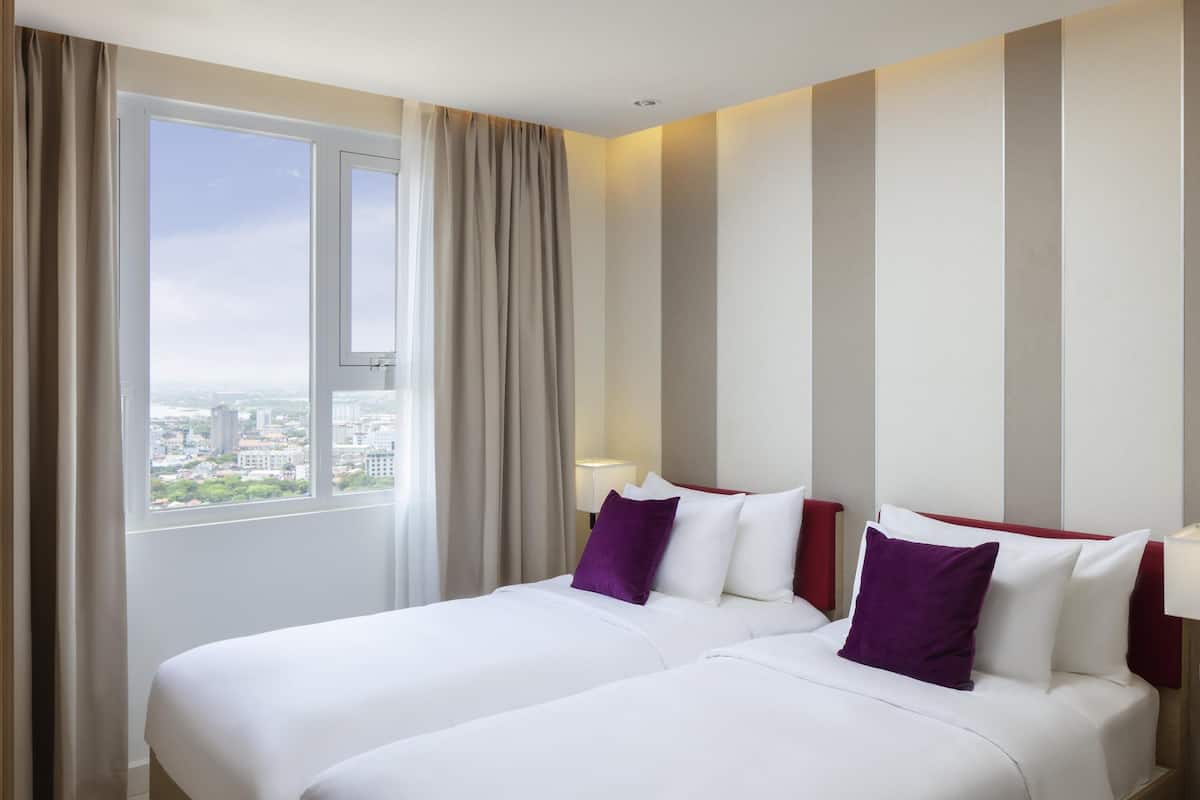 Een hotelkamer met twee bedden, een groot raam en uitzicht op de stad.