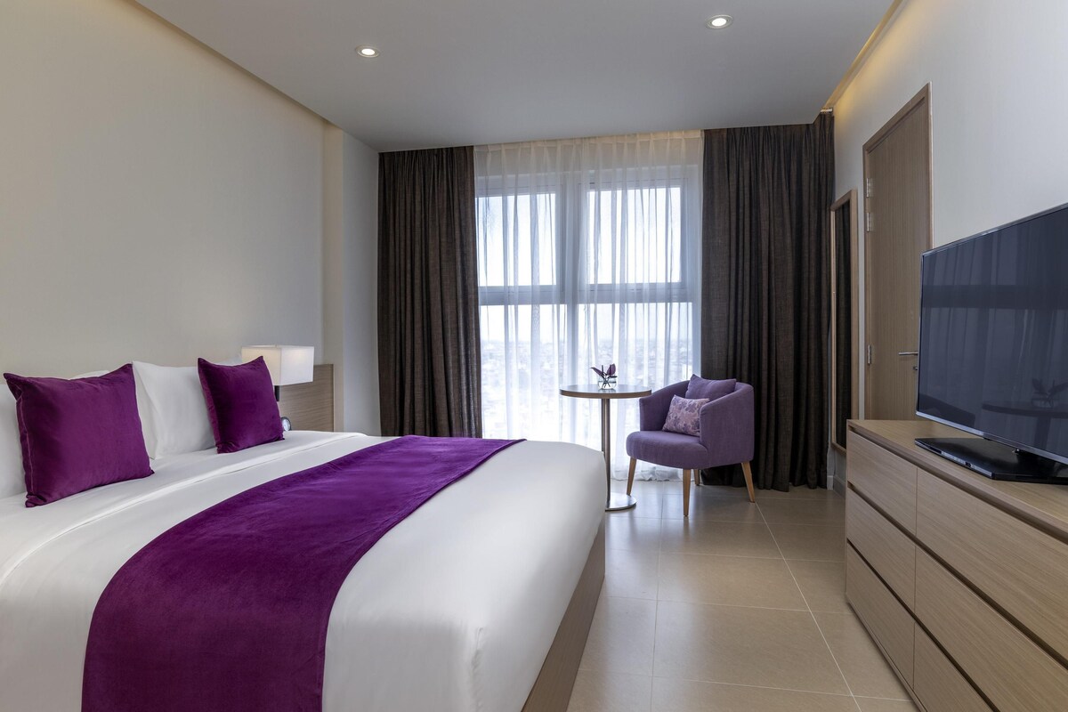 Een hotelkamer met een bed, een televisie, een klein tafeltje en een stoel.