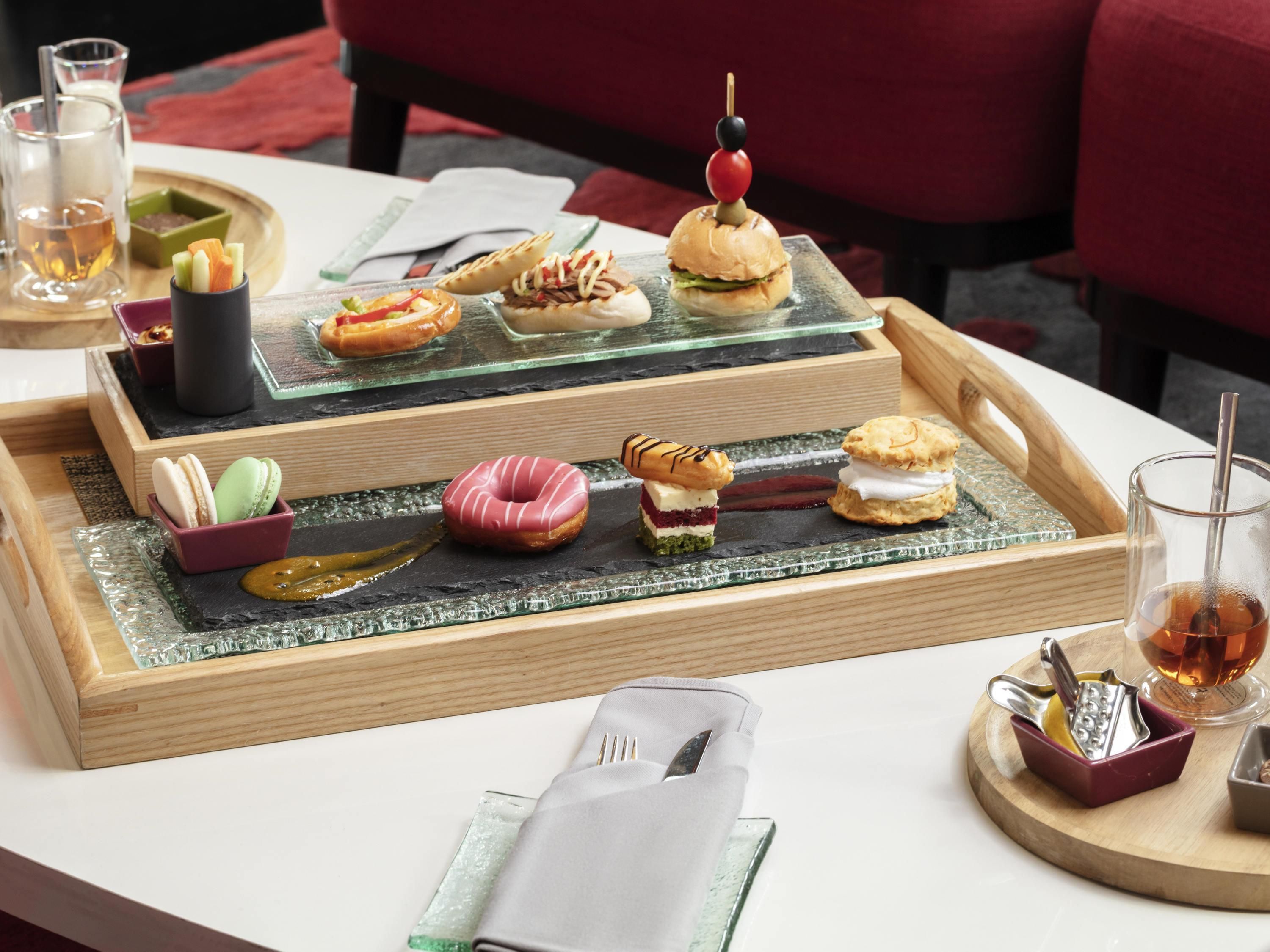 A tray with various snacks and a glass of tea on a table.