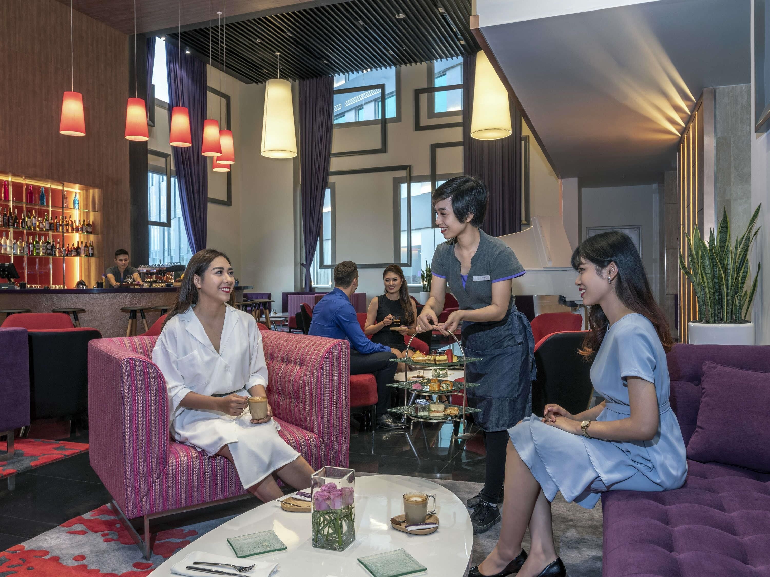 Ein stilvoller Lounge-Bereich mit Sitzgelegenheiten, einer Bar und einem Kellner, der Speisen serviert.
